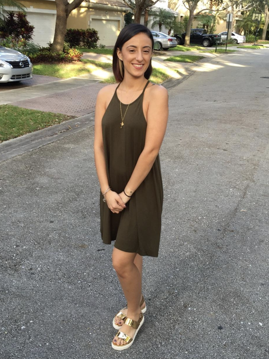 The reviewer is wearing an olive green dress.