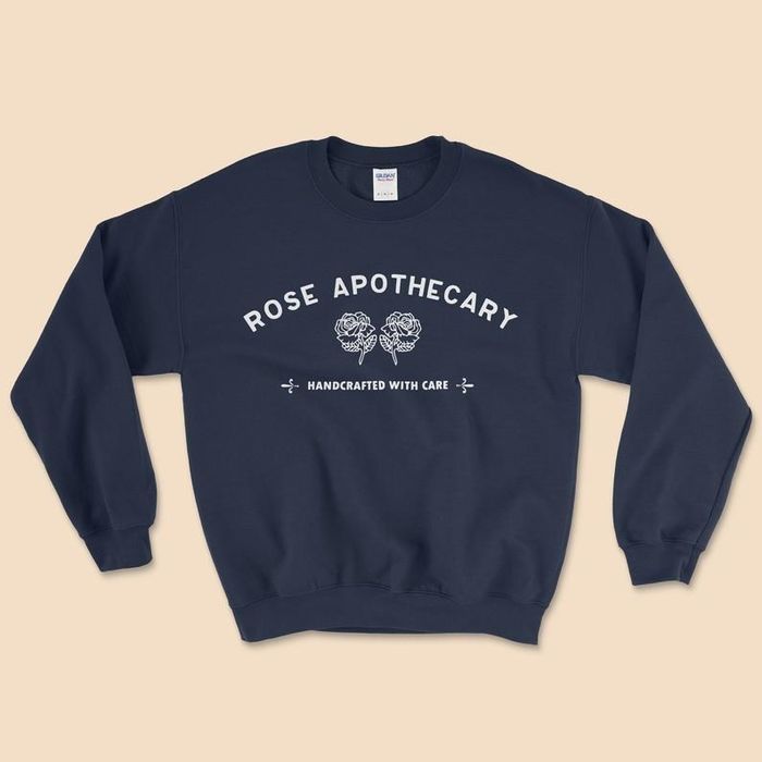 The black sweatshirt featuring the Rose Apothecary logo and the motto