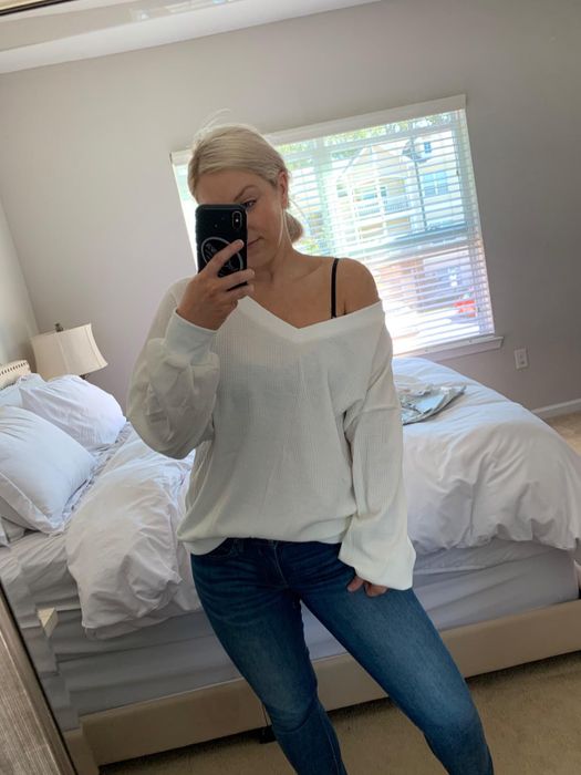 A reviewer photo of them wearing the white V-neck sweater off the shoulder