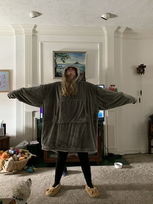 A reviewer wearing the grey sweatshirt, which reaches down to their knees