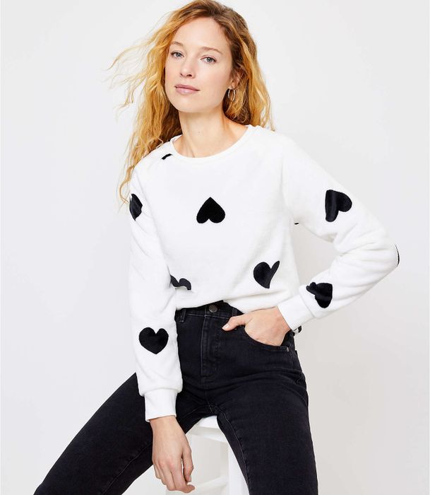 A model wearing the white sweatshirt featuring black novelty print hearts