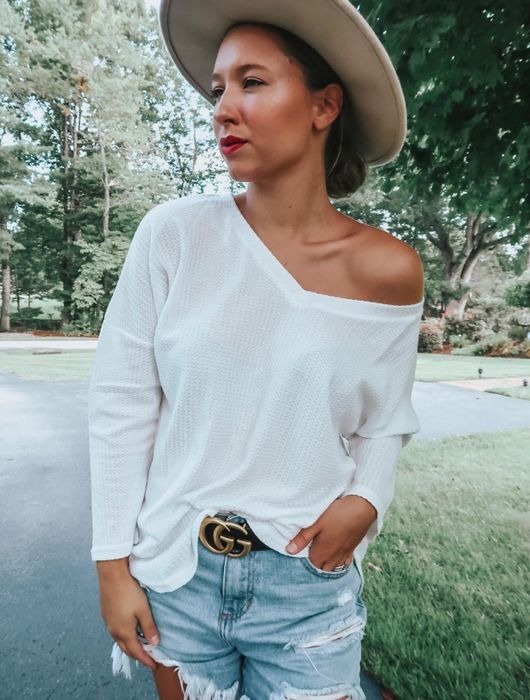 Another reviewer showcasing the white top, styled off the shoulder with denim shorts