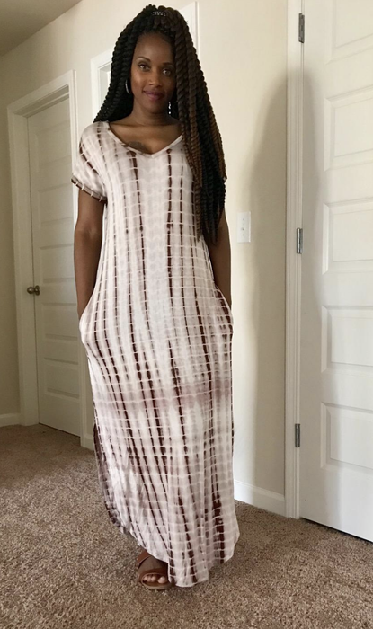 A reviewer shows off a pink and white dress with pockets.