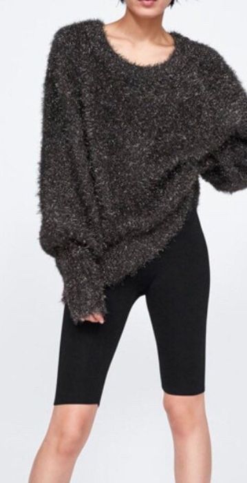 Model styled in black knee-length leggings paired with an oversized sweatshirt.