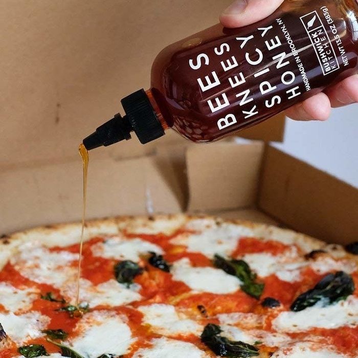 Pouring the spicy honey over a slice of pizza.