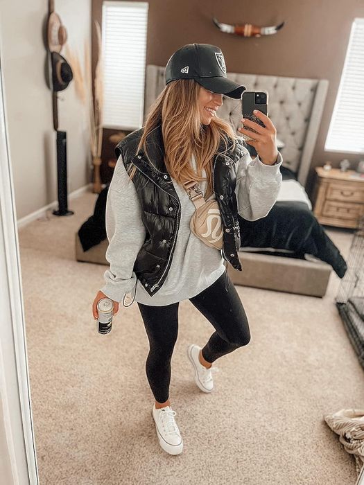 A reviewer wearing a gray oversized sweatshirt paired with leggings and a vest