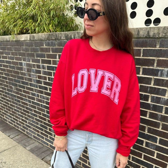 A model wearing a red sweatshirt with the text 