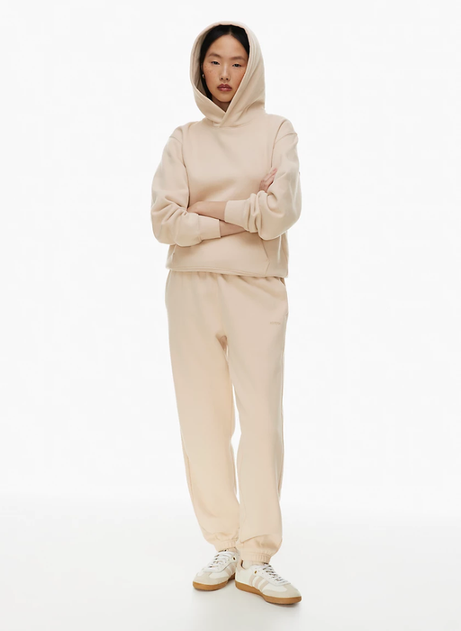 A person standing with arms crossed, wearing a casual hoodie and sweatpants