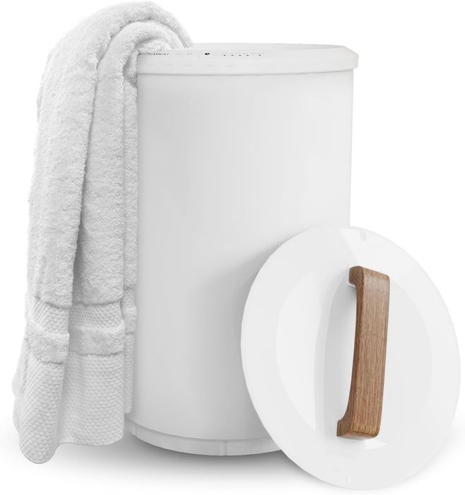 A white towel neatly placed on a cylindrical white laundry hamper featuring a wooden handle on the lid, highlighting stylish home organization