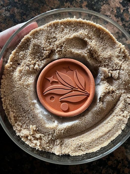 A reviewer's terracotta disc placed in a container of brown sugar