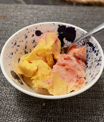 A close-up of a reviewer's vibrant yellow and red sorbet