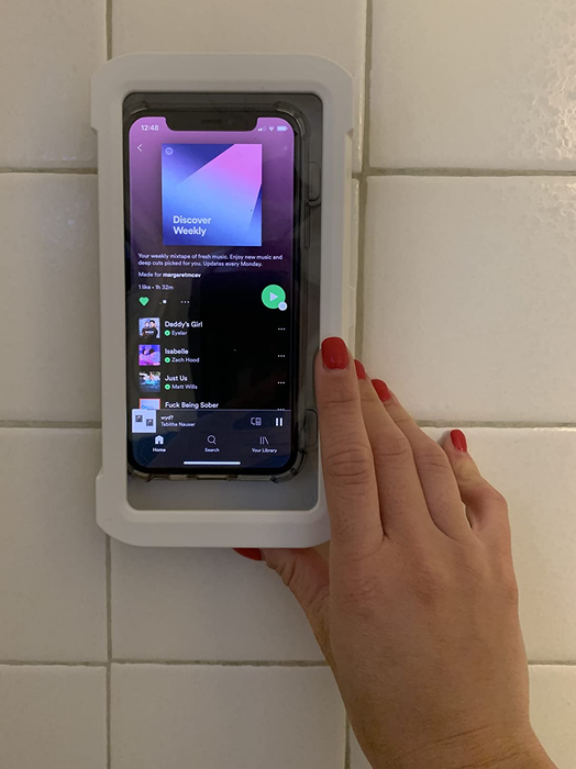 a reviewer is seen interacting with the exterior of the shower phone holder, which securely encases a smartphone