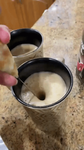 A reviewer demonstrating the frother in action, whipping milk into a creamy foam in a cup
