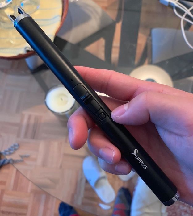 A reviewer's hand holding the sleek black lighter