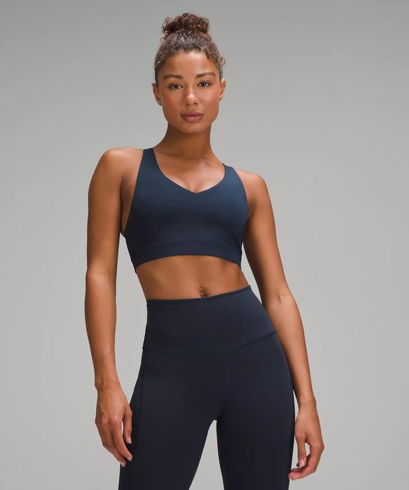 A woman models a high-waisted, seamless workout set, including a sports bra and leggings, showing off its sleek design.