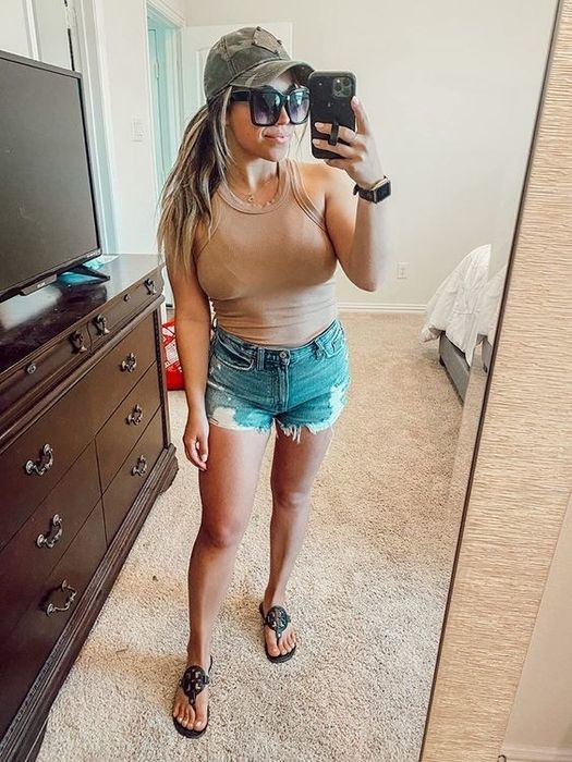 A reviewer wearing the tank top in a neutral beige shade