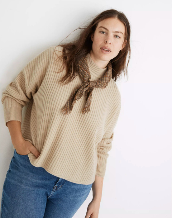 A model is seen wearing the mock-neck pullover in beige.