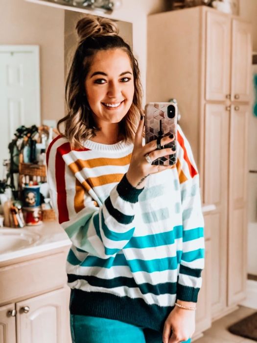 A reviewer modeling a gradient striped sweater