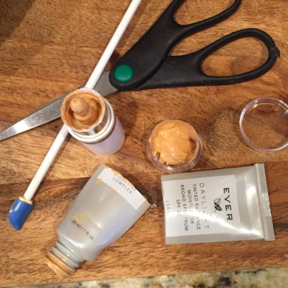 A reviewer's photo of a cut-open foundation bottle, a long-handled mini spatula, and a small jar filled with the saved foundation