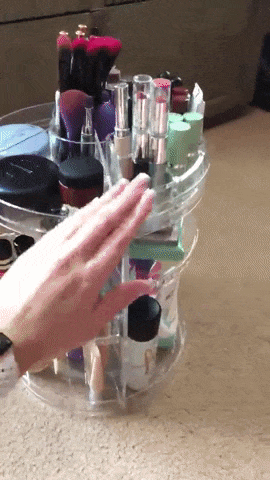 A reviewer demonstrating the clear acrylic organizer, spinning it to show the neatly arranged products inside