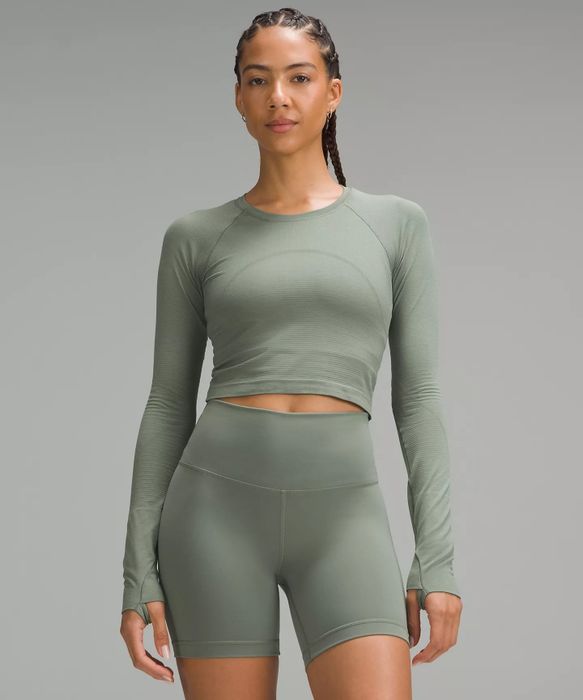 A person is wearing a long-sleeve crop top paired with matching high-waisted biker shorts, creating a sleek and sporty look.