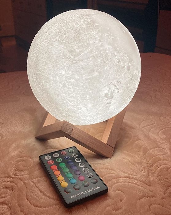 The glowing moon lamp on a wooden base, with a remote control beside it