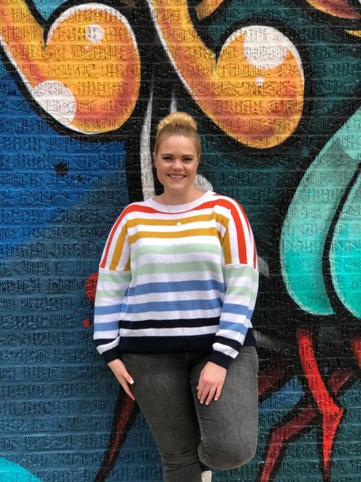 A reviewer is seen wearing the sweater in rainbow stripes.