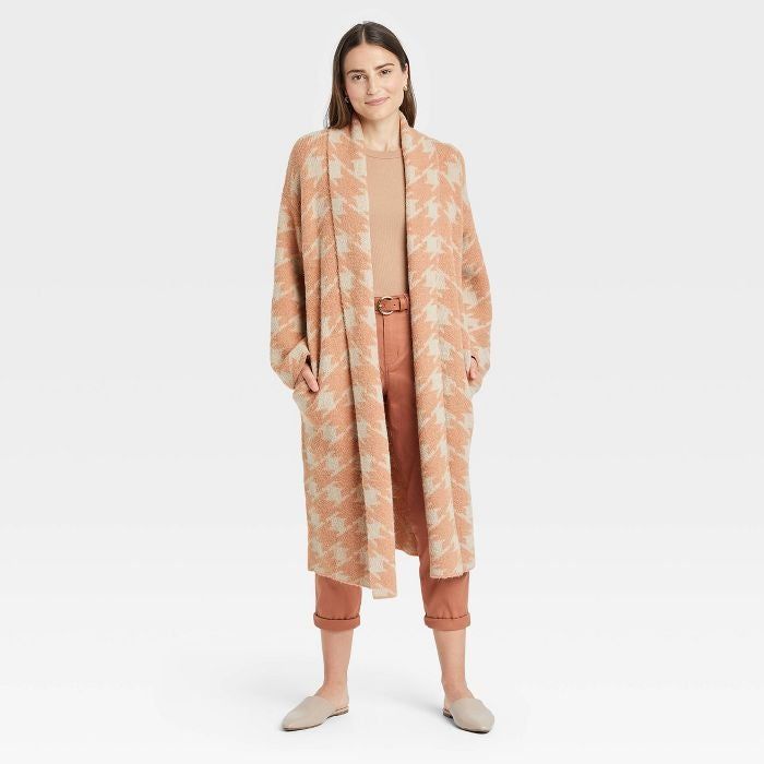 A model is seen wearing the houndstooth long cardigan in orange and beige.