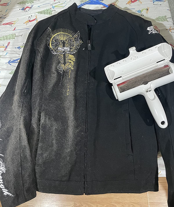 A reviewer's photo of the ChomChom resting on a black hoodie, with the left side covered in hair and the right side clean
