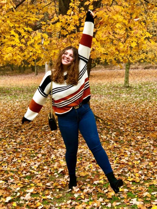 A reviewer is seen wearing the sweater with stripes in white, black, and dark orange.