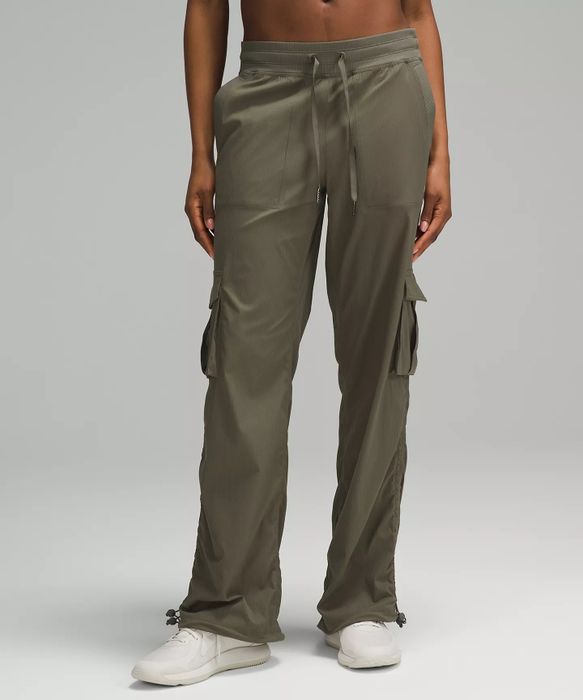 A person models olive green cargo pants with a drawstring waist, side pockets, and white sneakers. The article explores the trend of shopping for stylish and functional cargo pants.