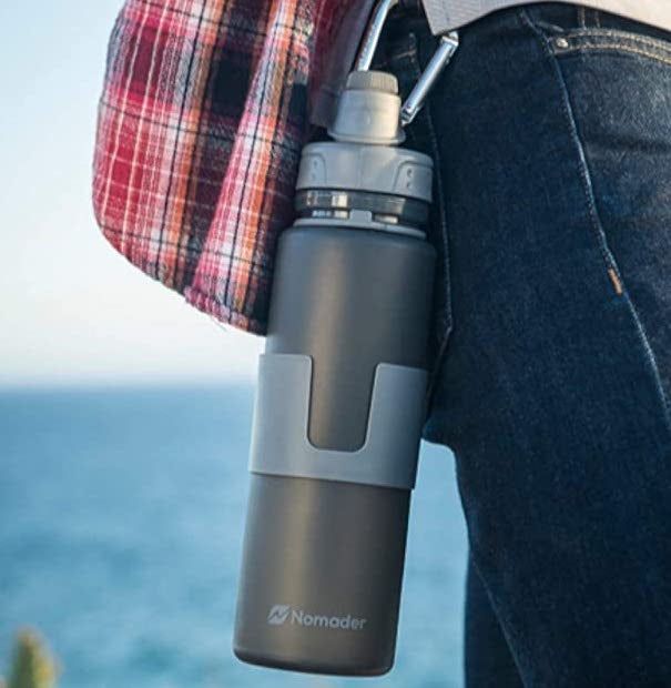 The expanded gray water bottle clipped onto a backpack