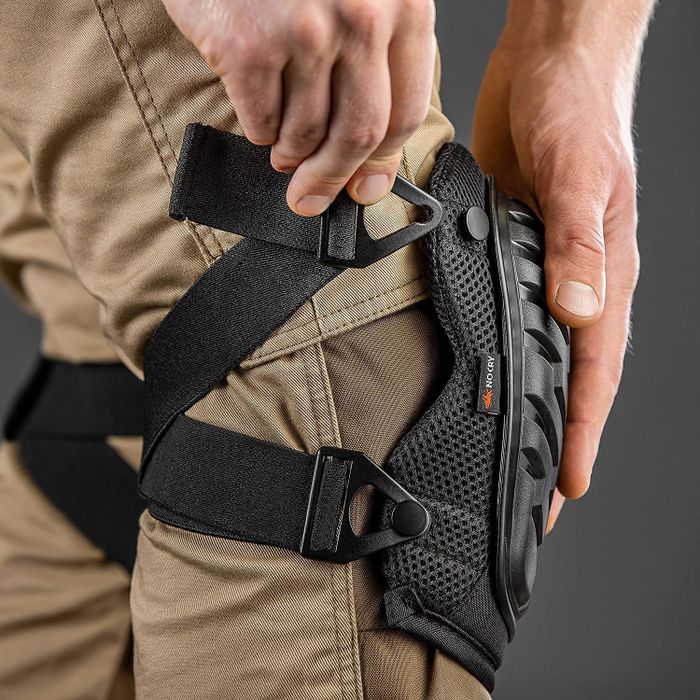 an individual securing knee pads over their trousers