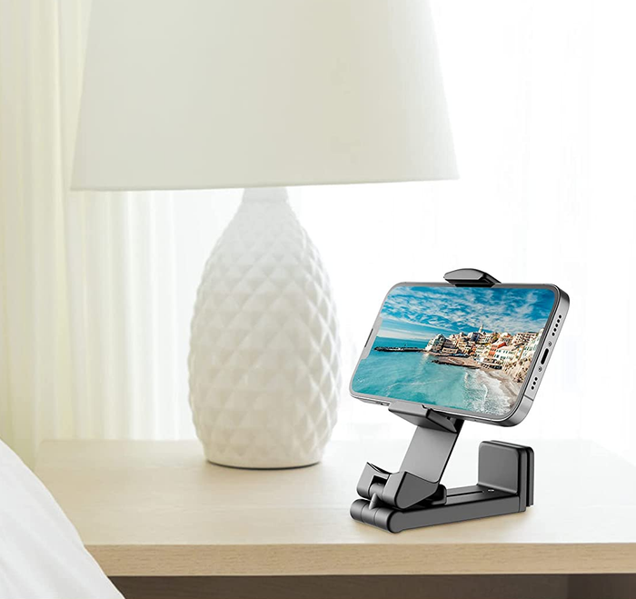 A black phone mount placed on a nightstand, holding a phone in place