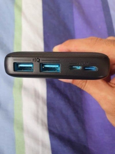 The reviewer proudly displaying a portable charger from the side, showcasing the charging ports for convenience.