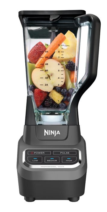 A blender filled with various fruits, showcasing measurement markings and buttons on the base to adjust blending settings.