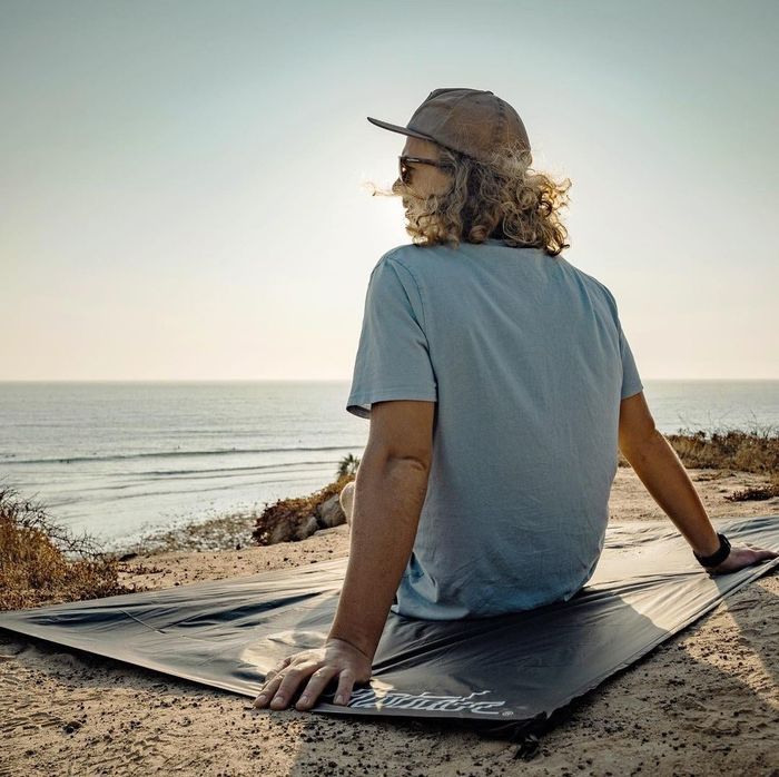 A person relaxing on a blanket while gazing out over the ocean, taking in the peaceful view.