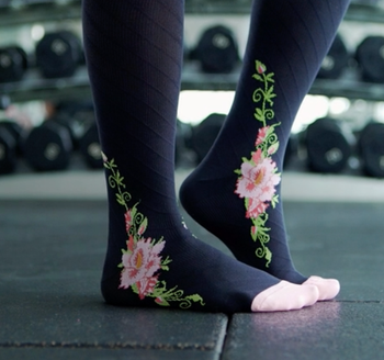 A model wearing black socks with a stylish pink floral design.