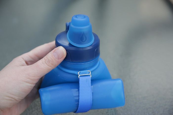 A reviewer demonstrates the compact rolled-up water bottle, showing its portability.