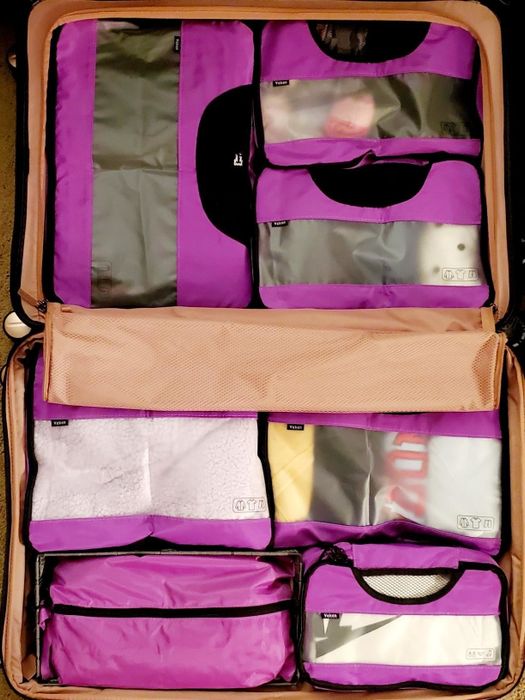 A reviewer's bag organized with neat purple packing cubes, maximizing suitcase space.