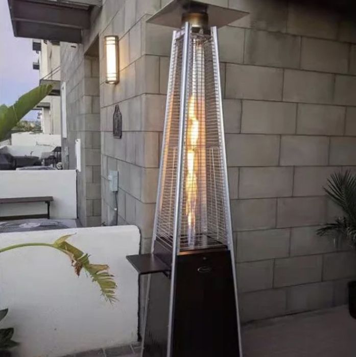 A stylish patio heater with a warm flame inside a glass tube, providing both heat and ambiance next to the outdoor furniture.