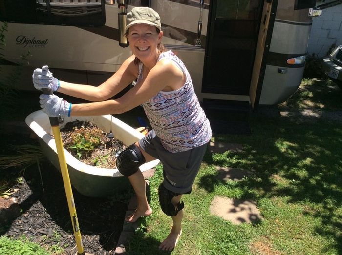 a satisfied reviewer grinning as they garden while wearing the knee pads