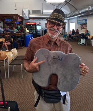 A reviewer showing off the cushion while at the airport, ready for ultimate comfort.