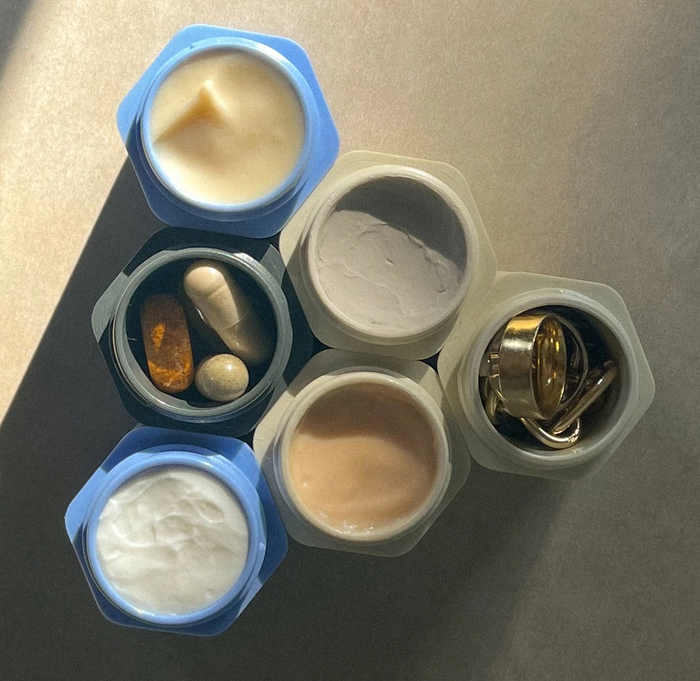 A top-down view of six open containers filled with items such as medications, skincare essentials, and jewelry.