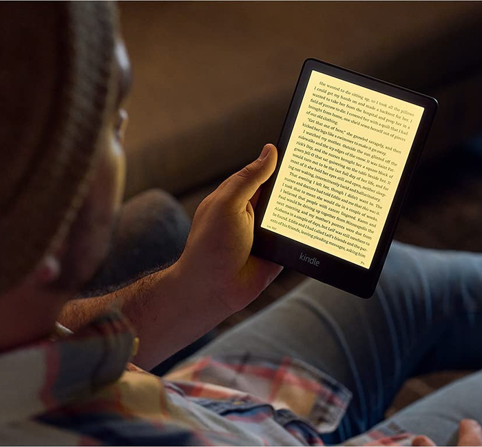 A model reading a book on the Kindle Paperwhite, showcasing its illuminated screen for nighttime reading