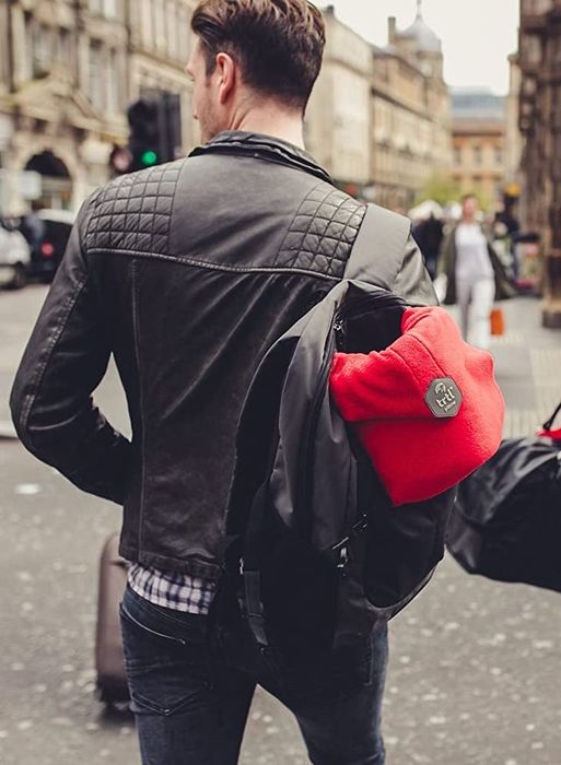 A model with a red Trtl pillow attached to their backpack, showcasing its portability