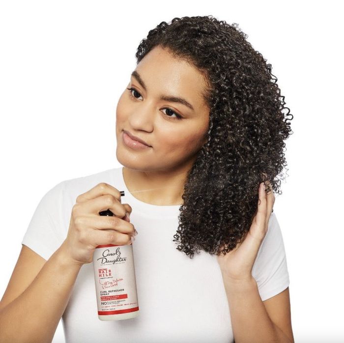 A person applying hair milk to their strands