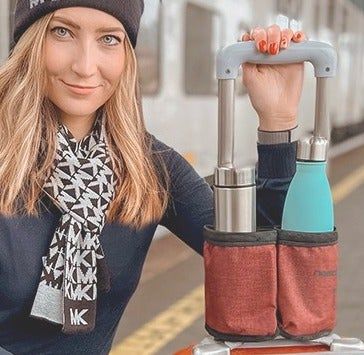 A model standing beside a suitcase with the innovative cup holder securely fastened to its handle