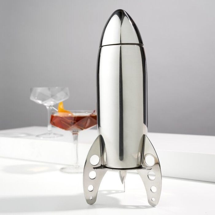 A silver cocktail shaker in the shape of a rocket, blending space-age style with function.