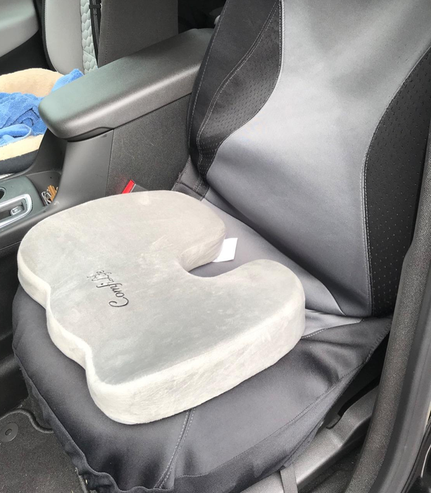 A reviewer's photo of the gray seat cushion placed on a car seat